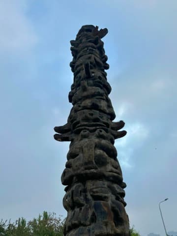 Carved pole against a grey sky, AI edit